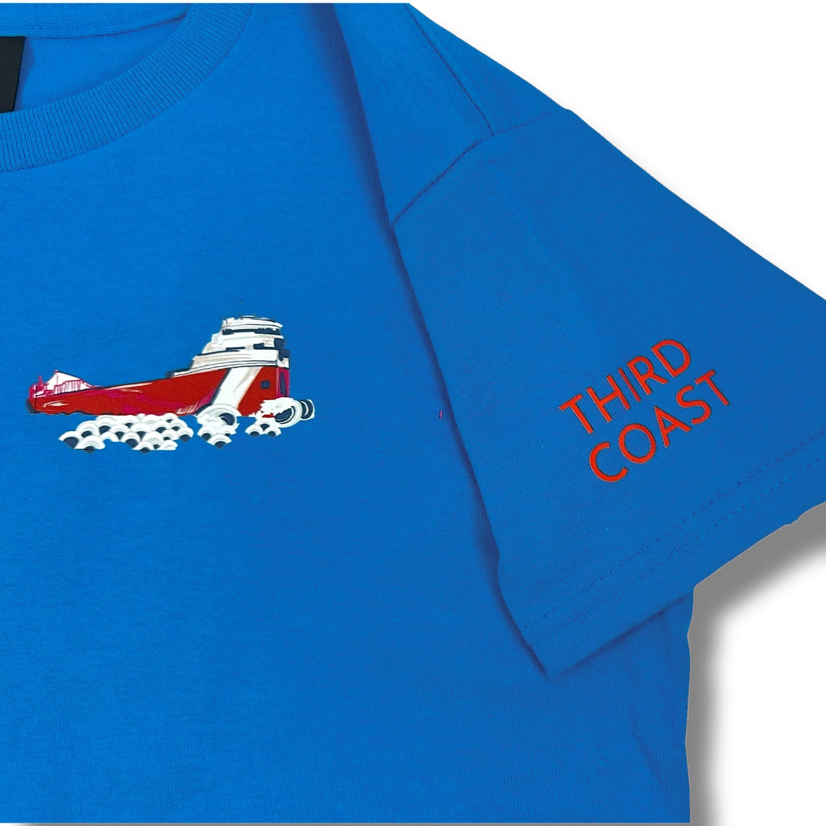 Close-up of the TWAL blue youth t-shirt showing the freighter graphic on the chest and Third Coast text on the sleeve